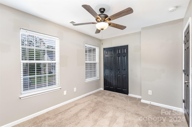 unfurnished bedroom with light carpet, a closet, and ceiling fan