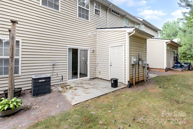 back of property featuring cooling unit, a lawn, and a patio area