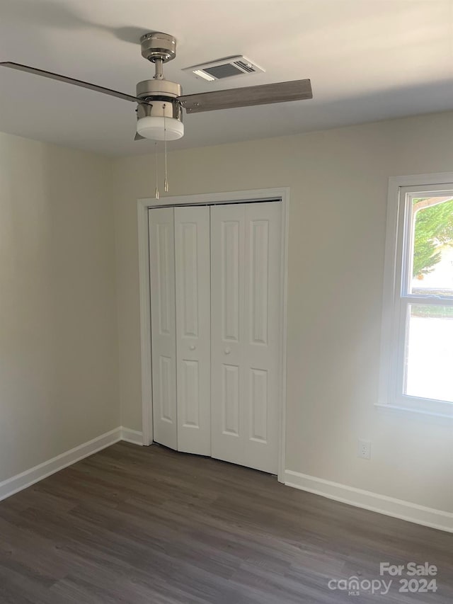 unfurnished bedroom featuring dark wood-type flooring, ceiling fan, and a closet