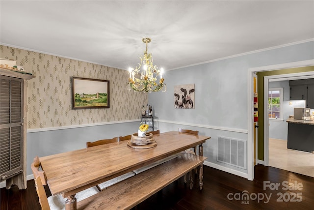 dining room with dark wood-type flooring, ornamental molding, and a chandelier