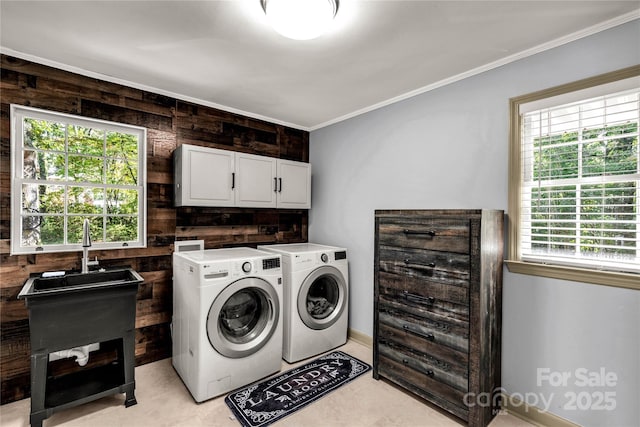 laundry area with ornamental molding, wooden walls, washing machine and dryer, and cabinets