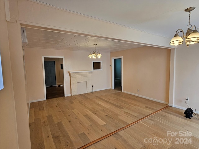 unfurnished living room with an inviting chandelier and wood-type flooring