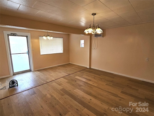 unfurnished dining area with hardwood / wood-style flooring and a notable chandelier