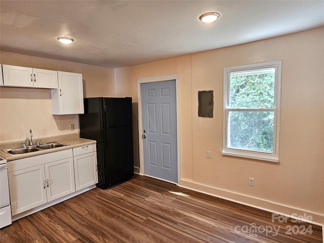 kitchen with dark wood-type flooring, sink, black refrigerator, and white cabinetry