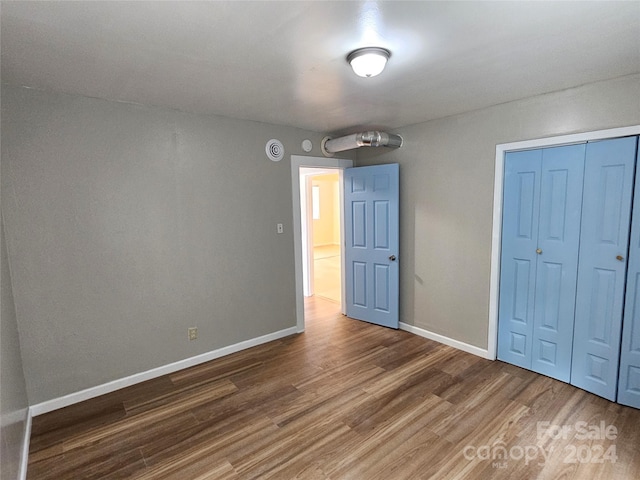 unfurnished bedroom with a closet and hardwood / wood-style flooring