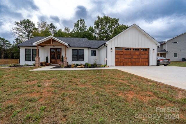 modern farmhouse featuring a garage and a front lawn