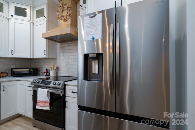 kitchen featuring appliances with stainless steel finishes, tasteful backsplash, custom exhaust hood, and white cabinets