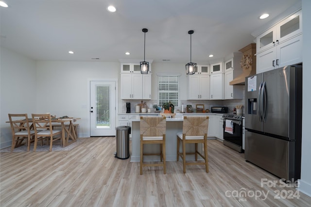 kitchen with pendant lighting, stainless steel appliances, white cabinetry, and a kitchen island