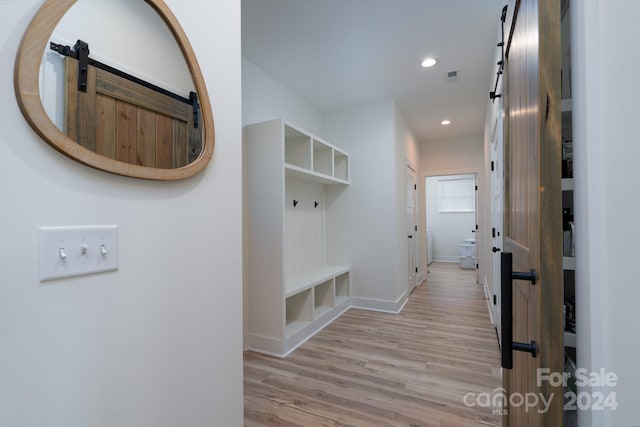 mudroom with light wood-type flooring and a barn door