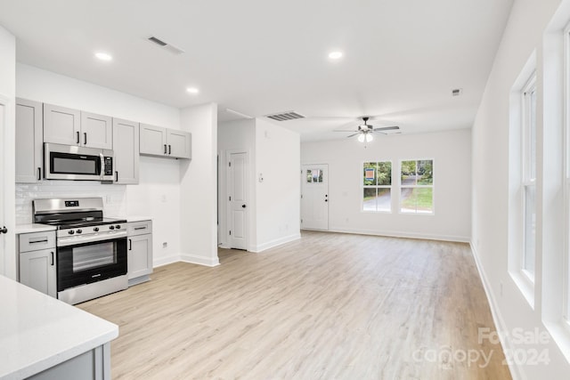 kitchen with gray cabinetry, stainless steel appliances, ceiling fan, and light wood-type flooring