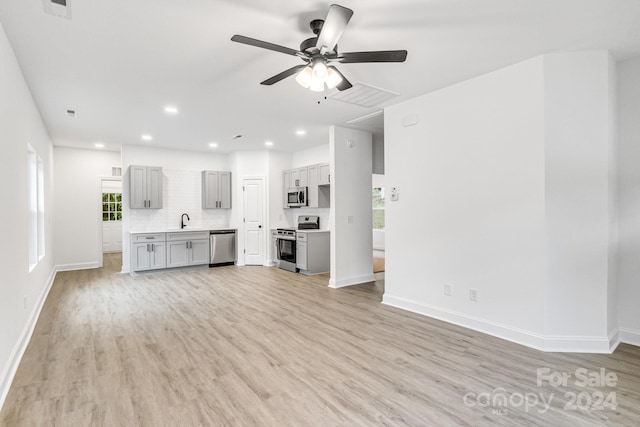 unfurnished living room with light wood-type flooring, ceiling fan, and sink