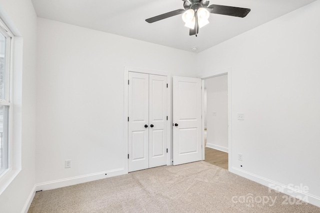 unfurnished bedroom with ceiling fan, light colored carpet, and a closet