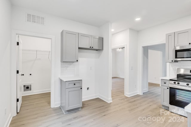 kitchen featuring gray cabinetry, decorative backsplash, light hardwood / wood-style flooring, and stainless steel appliances