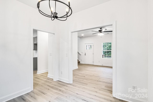 interior space with ceiling fan with notable chandelier and light hardwood / wood-style flooring