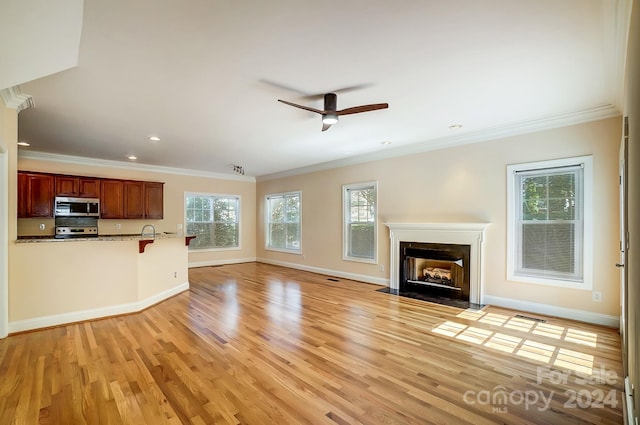 unfurnished living room featuring crown molding, plenty of natural light, and light hardwood / wood-style floors