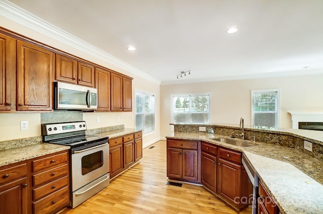 kitchen with light stone counters, ornamental molding, sink, stainless steel appliances, and light hardwood / wood-style floors