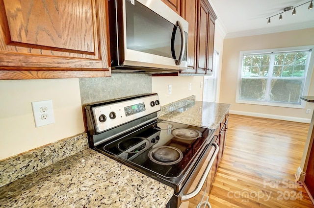 kitchen featuring light stone counters, crown molding, stainless steel appliances, and light hardwood / wood-style flooring