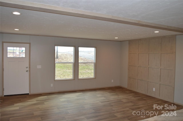 entrance foyer with beamed ceiling, wood-type flooring, a textured ceiling, and a wealth of natural light