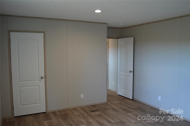 unfurnished bedroom with hardwood / wood-style floors and ornamental molding