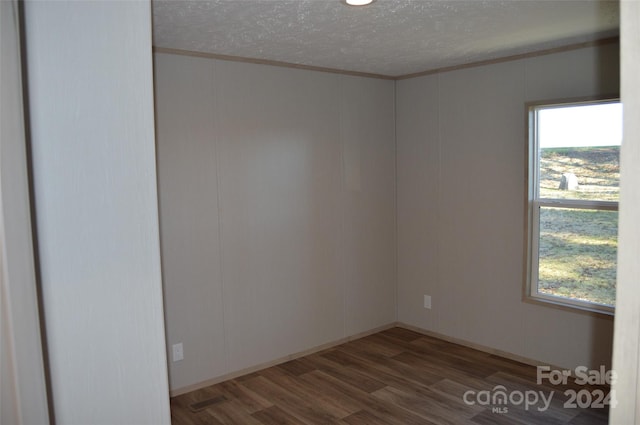 spare room with dark wood-type flooring, a textured ceiling, and ornamental molding