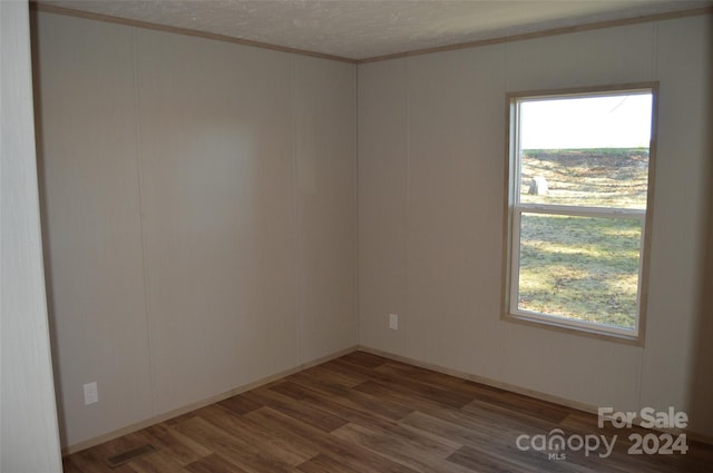 empty room featuring crown molding, plenty of natural light, and dark hardwood / wood-style floors