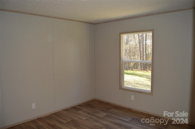 empty room with wood-type flooring and crown molding