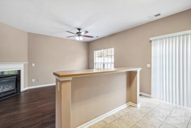 kitchen featuring ceiling fan, light hardwood / wood-style flooring, a fireplace, and a kitchen island