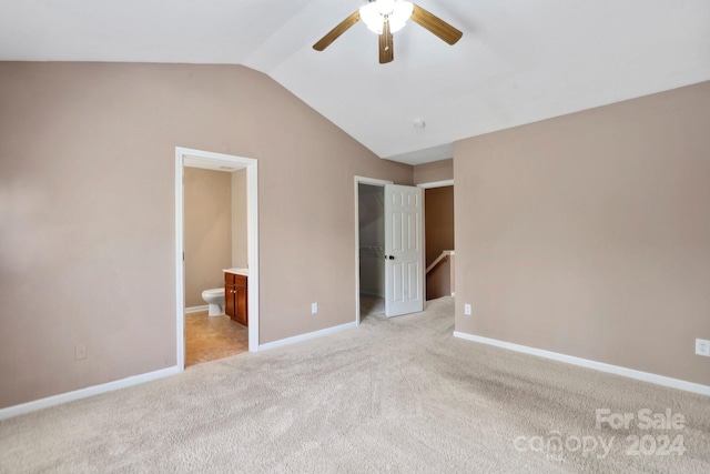 unfurnished bedroom featuring light colored carpet, vaulted ceiling, ceiling fan, and ensuite bathroom