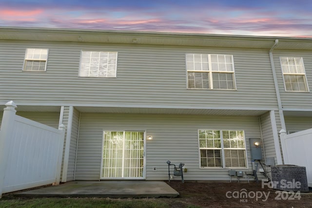 back house at dusk featuring cooling unit and a patio area