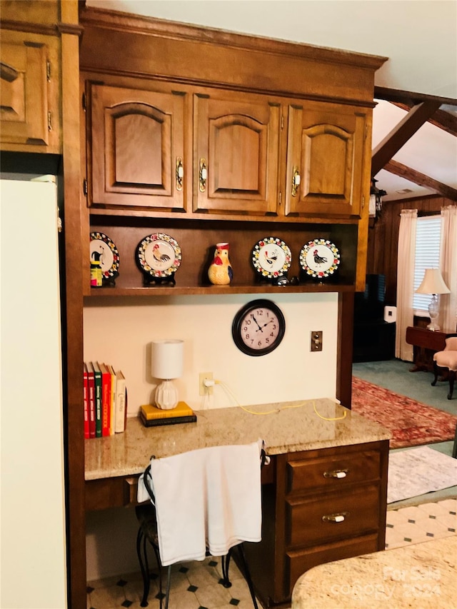 kitchen with light stone countertops, built in desk, and white refrigerator