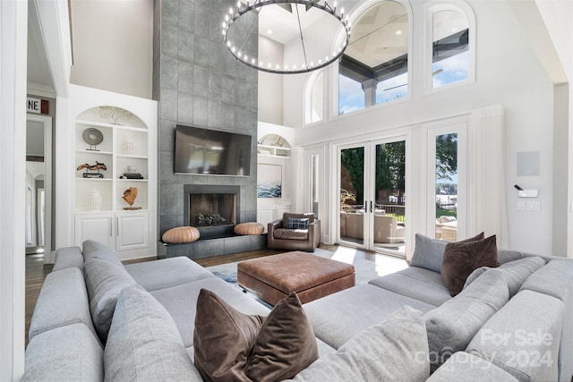 living room featuring built in shelves, a towering ceiling, a fireplace, and a healthy amount of sunlight