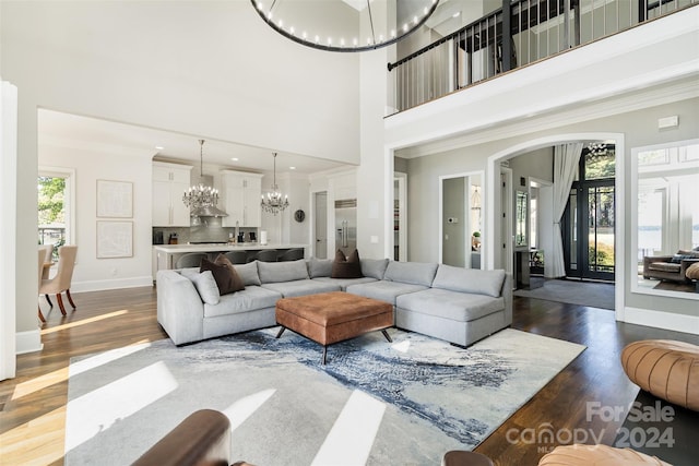 living room featuring ornamental molding, a towering ceiling, dark hardwood / wood-style flooring, and a notable chandelier