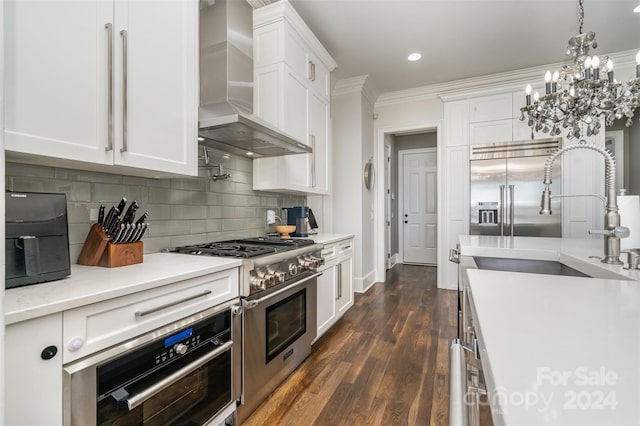 kitchen with ornamental molding, wall chimney exhaust hood, dark hardwood / wood-style floors, high end appliances, and white cabinets