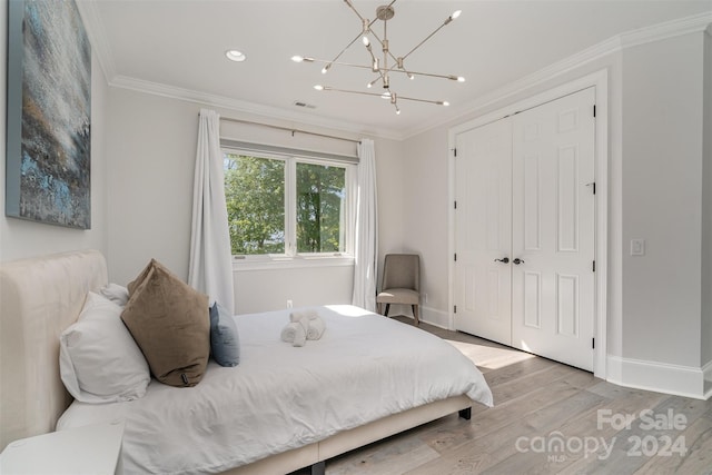 bedroom with ornamental molding, a closet, an inviting chandelier, and light hardwood / wood-style floors