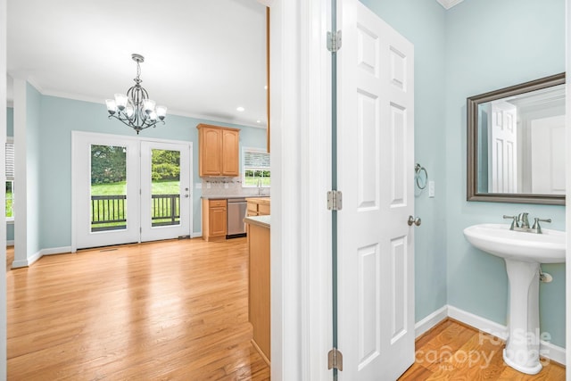 bathroom with sink, tasteful backsplash, crown molding, wood-type flooring, and an inviting chandelier