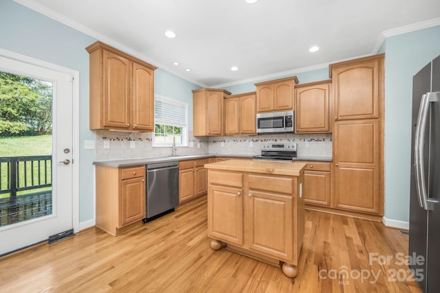 kitchen featuring tasteful backsplash, ornamental molding, a center island, stainless steel appliances, and light hardwood / wood-style flooring