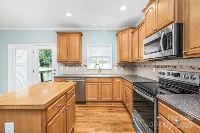 kitchen with sink, backsplash, light hardwood / wood-style floors, stainless steel appliances, and crown molding