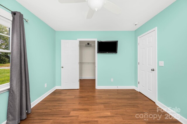 unfurnished bedroom featuring hardwood / wood-style flooring, a spacious closet, ceiling fan, and a closet