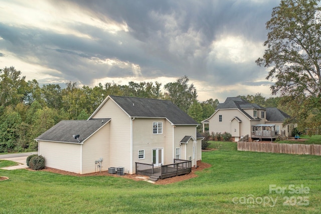 rear view of property featuring a wooden deck, a yard, and central air condition unit