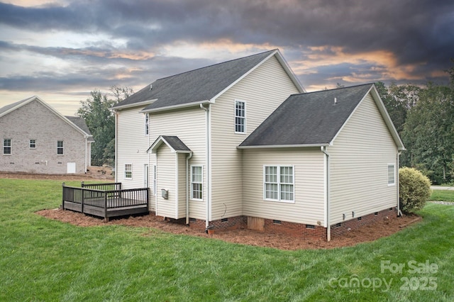 back house at dusk featuring a yard and a deck