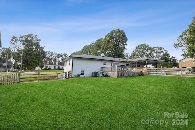 back of property with a yard, a deck, and central air condition unit