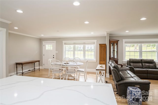 dining space with ornamental molding and light hardwood / wood-style flooring