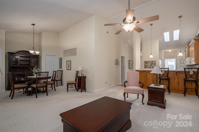 carpeted living room with ceiling fan, a skylight, and high vaulted ceiling