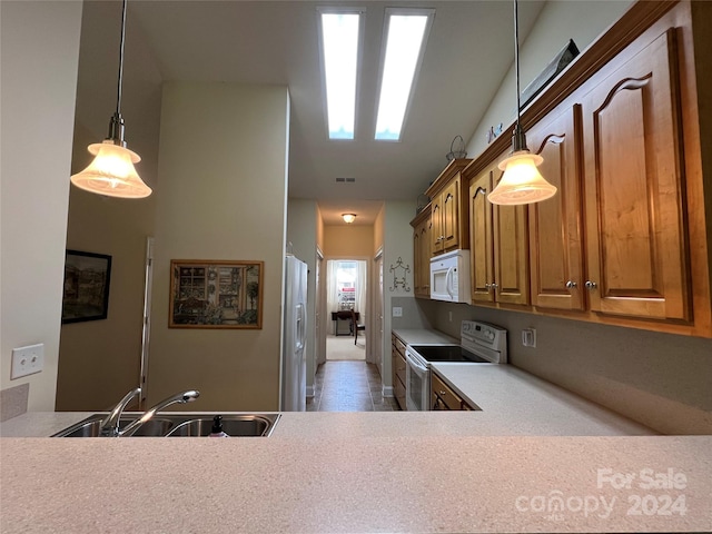 kitchen with white appliances, hanging light fixtures, sink, and kitchen peninsula