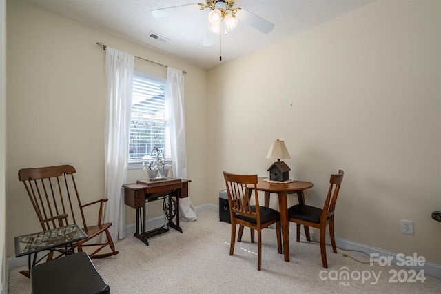 dining room featuring ceiling fan, light colored carpet, and a textured ceiling