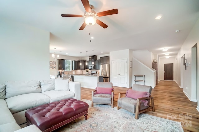 living room with light hardwood / wood-style floors and ceiling fan