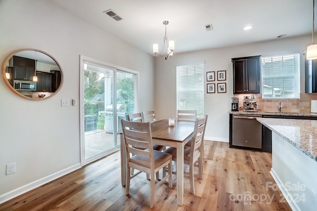 dining space with an inviting chandelier, light hardwood / wood-style flooring, and sink