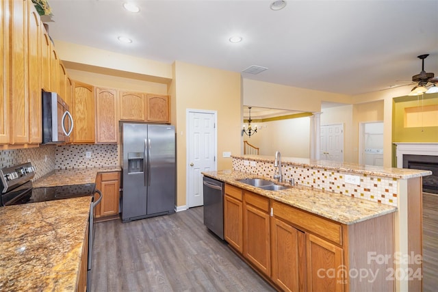 kitchen with sink, dark wood-type flooring, stainless steel appliances, backsplash, and a kitchen island with sink