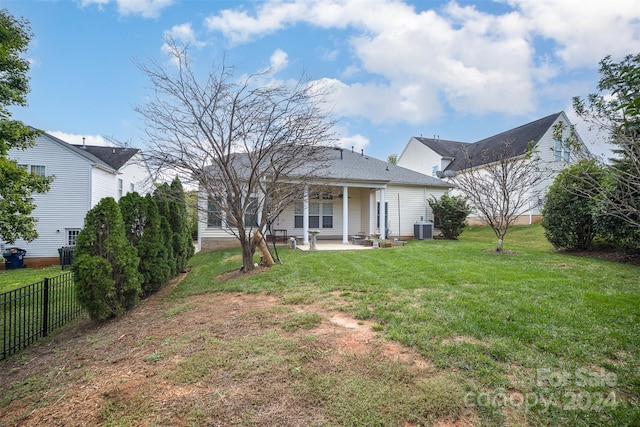 rear view of house with central AC unit, a patio area, and a lawn