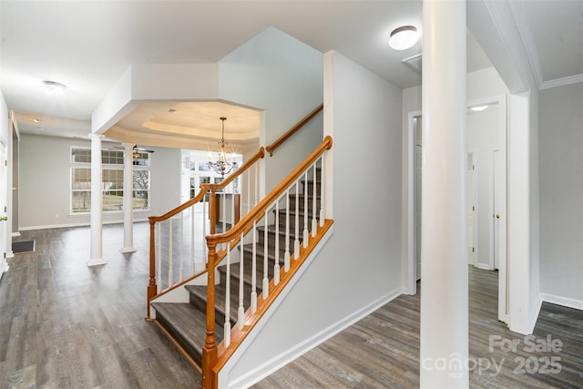 stairway with a notable chandelier, hardwood / wood-style flooring, and decorative columns